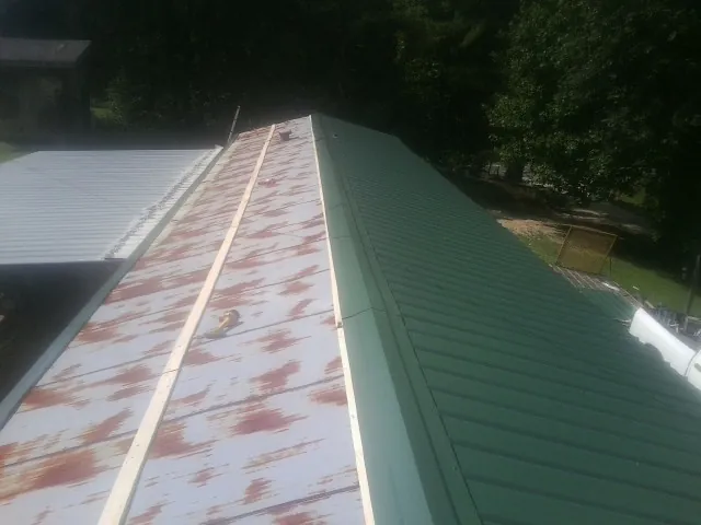 Old rusted panels beside newly installed green metal roofing — Wind Damage Roof Repair by Roofing Brothers in La Grange