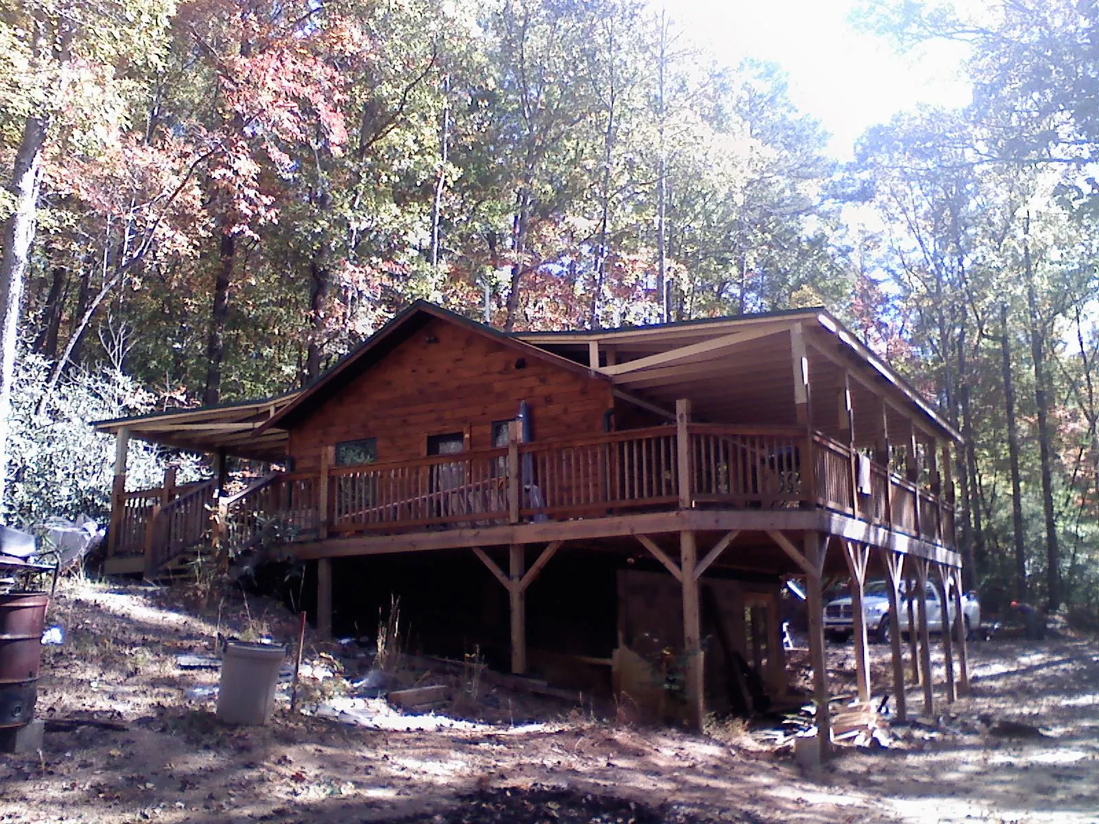 Log cabin with a wraparound porch and metal roof in the fall in La Grange